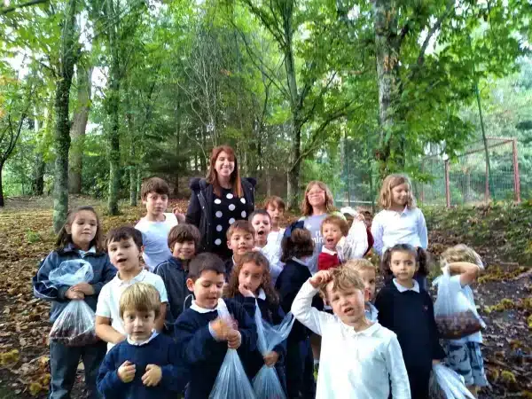 Grupo de alumnos con su profesora en el bosque sosteniendo bolsas con castañas