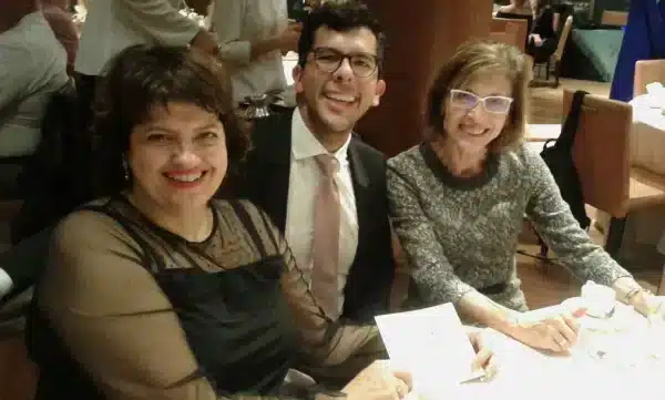 Tres docentes sonriendo sentados a la mesa durante una cena formal del colegio