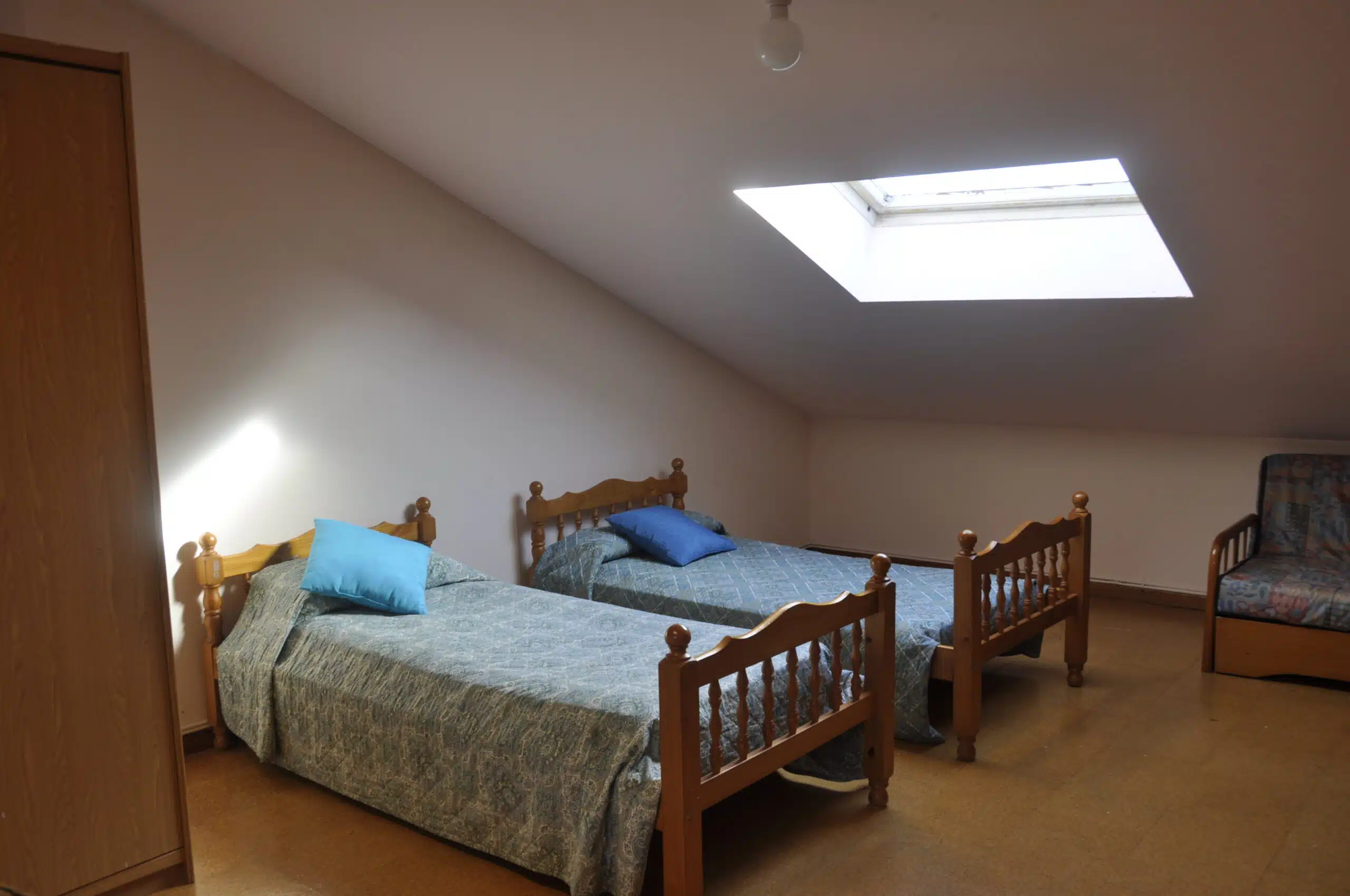 Dormitorio luminoso con dos camas individuales y techo abuhardillado en la residencia de estudiantes